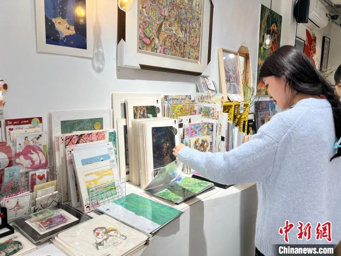 圖為藝術(shù)品商店內(nèi)，顧客挑選插畫作品?！＄婌?攝