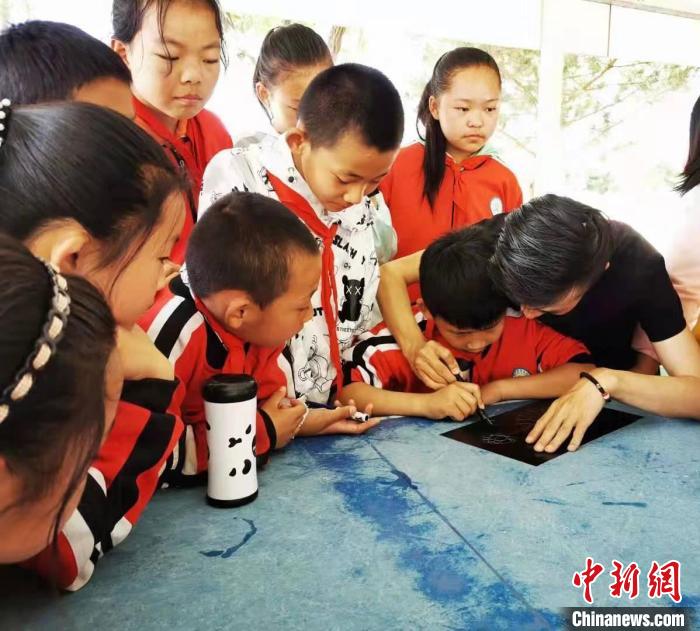 圖為朱增平(右一)教學(xué)生創(chuàng)作鍥金畫。(資料圖) 受訪者供圖