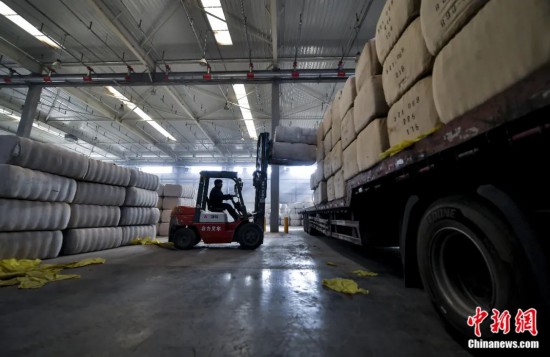新疆喀什綜合保稅區(qū)，喀什啟路國際貿(mào)易有限公司的倉庫內(nèi)，工人正在裝載從塔吉克斯坦和烏茲別克斯坦進口的棉花。劉新攝