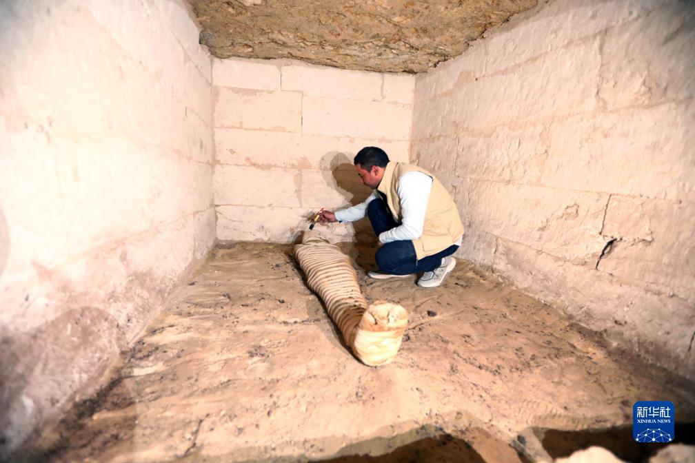 10月15日，在埃及明亞省考古現(xiàn)場，考古人員清理一座石鑿墓中的木乃伊。新華社發(fā)（艾哈邁德·戈馬攝）