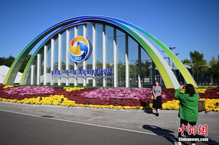 10月15日，北京，工作人員在國家會議中心外的第三屆“一帶一路”國際合作高峰論壇景觀布置前拍照留念。當日，位于國家會議中心的第三屆“一帶一路”國際合作高峰論壇新聞中心啟動試運行。據(jù)悉，第三屆“一帶一路”國際合作高峰論壇將于10月17日至18日在北京舉行。<a target='_blank' href='/'><p  align=