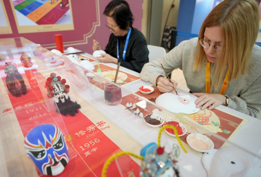 10月16日，在第三屆“一帶一路”國(guó)際合作高峰論壇新聞中心，來自比利時(shí)的記者（右）體驗(yàn)畫京劇臉譜。新華社記者 王毓國(guó) 攝