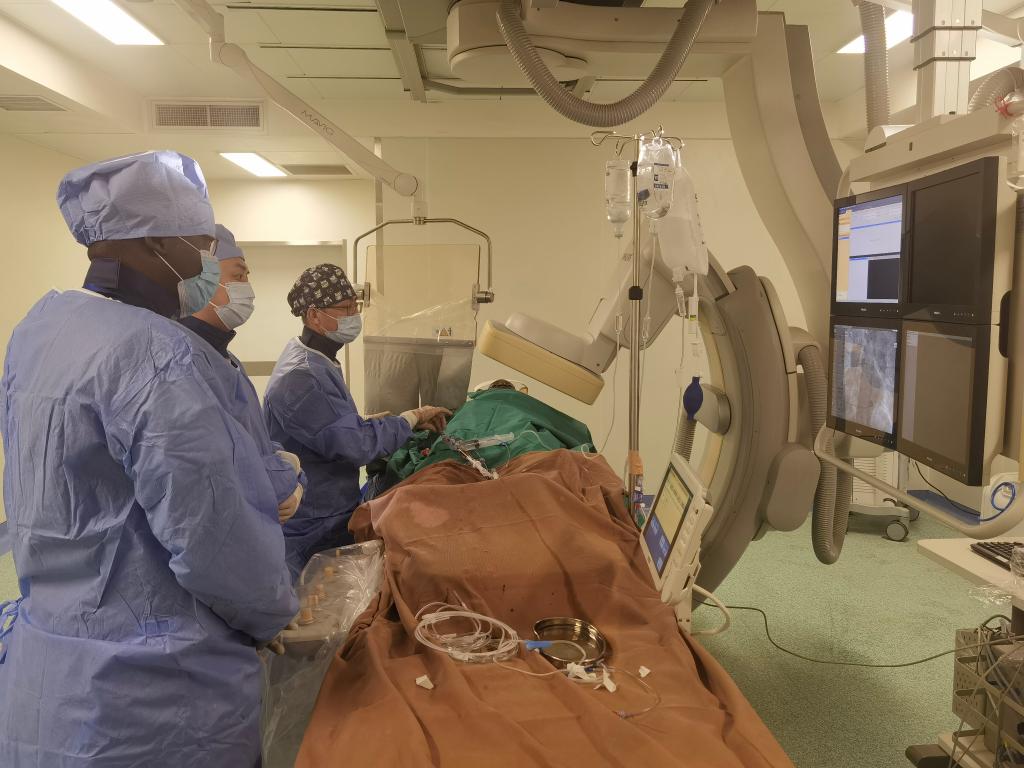 中國第29批援幾內(nèi)亞醫(yī)療隊隊員、首都醫(yī)科大學(xué)附屬北京天壇醫(yī)院心內(nèi)科副主任醫(yī)師王汝朋（右一）正在給患者做手術(shù)。（北京天壇醫(yī)院供圖）