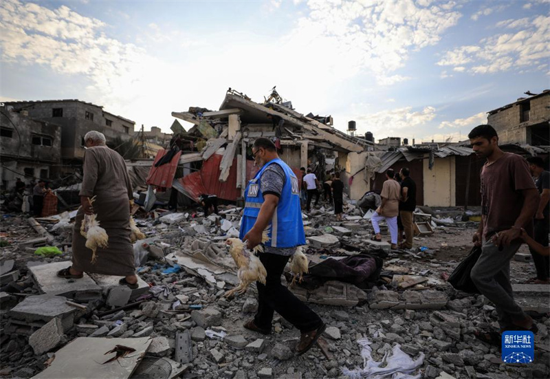 10月27日，在加沙地帶南部城市汗尤尼斯，人們經(jīng)過以軍襲擊后的房屋廢墟。