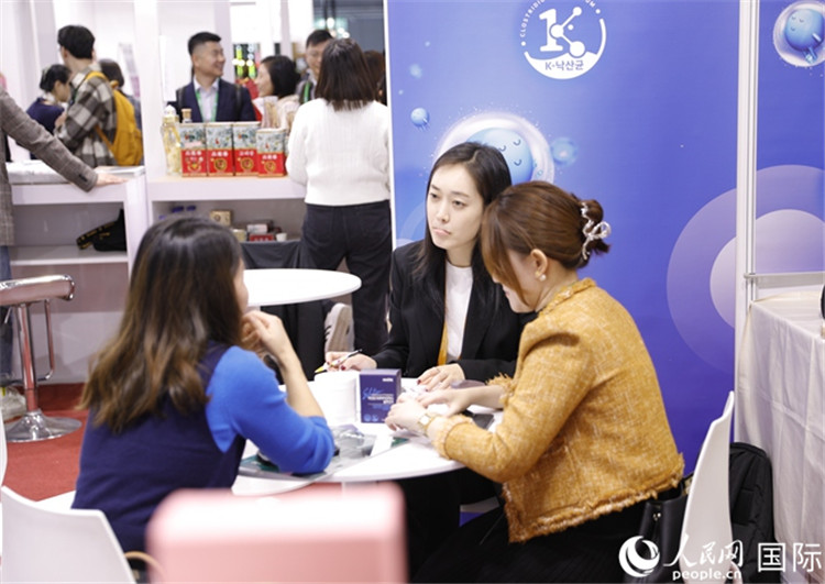 圖2:金相俊同事在展臺同客商洽談 人民網(wǎng)記者 李美玉攝