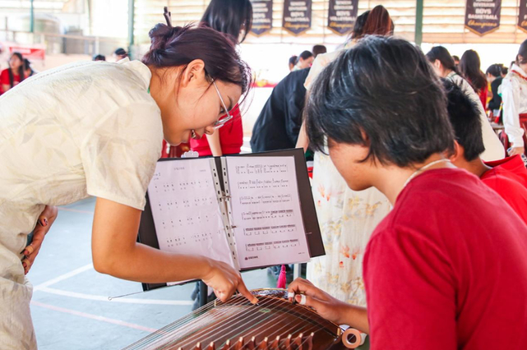 志愿者教師指導(dǎo)學(xué)生彈奏古箏?；顒又鬓k方供圖