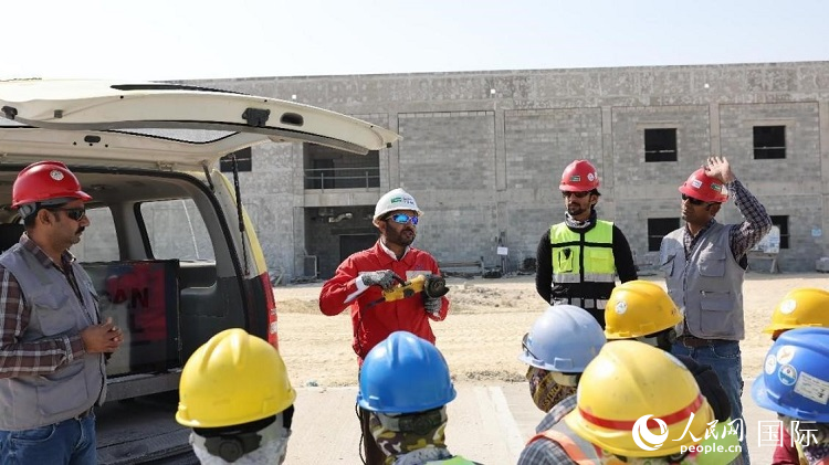 穆薩瓦爾(圖中紅衣人）現(xiàn)場(chǎng)演示工具操作規(guī)范。人民網(wǎng)記者 管克江攝