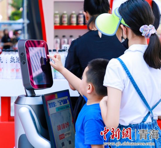 圖為一名小朋友正在和機(jī)器人“志愿者”進(jìn)行互動(dòng)。 沐聞 攝