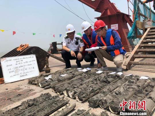 圖為勘察設(shè)計人員與海事局工作人員查看巖芯情況?！∥赫?攝