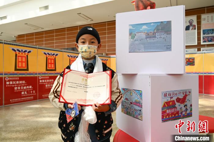圖為一名獲獎(jiǎng)學(xué)生與自己的繪畫作品合影。　趙朗 攝