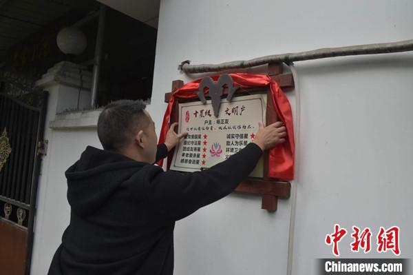 桂溪鎮(zhèn)渭溝村政府工作人員為“十星級文明戶”掛上牌匾?!钣?攝