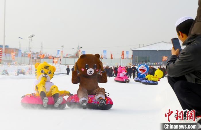 圖為臨夏市南龍鎮(zhèn)馬家莊村舉辦的鄉(xiāng)村文化旅游節(jié)上，游客穿著卡通服裝在體驗(yàn)雪上飛碟項(xiàng)目。近年來(lái)，臨夏州形成了“春賞花、夏避暑、秋摘果、冬玩雪”的全季節(jié)旅游產(chǎn)品體系。(資料圖) 高展 攝