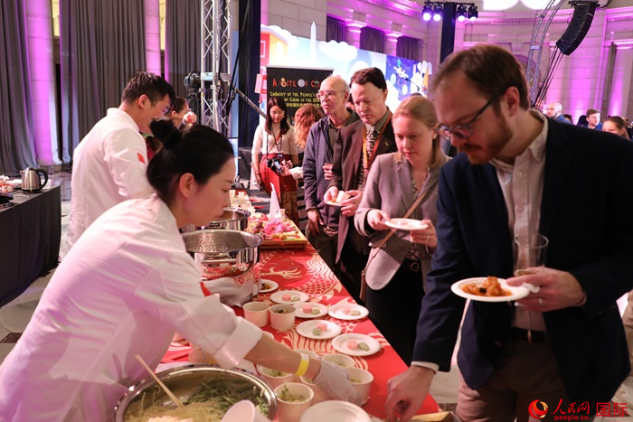 當(dāng)?shù)貢r(shí)間3月7日晚，華盛頓聯(lián)合車站廣場舉行駐美使團(tuán)“使館主廚挑戰(zhàn)賽”。圖為當(dāng)?shù)孛癖娫谥袊古_前體驗(yàn)中國美食。人民網(wǎng)記者 李志偉攝