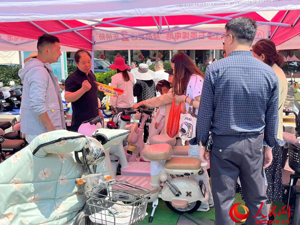 某電動自行車品牌工作人員向消費者介紹以舊換新相關情況。人民網(wǎng)記者 杜燕飛攝