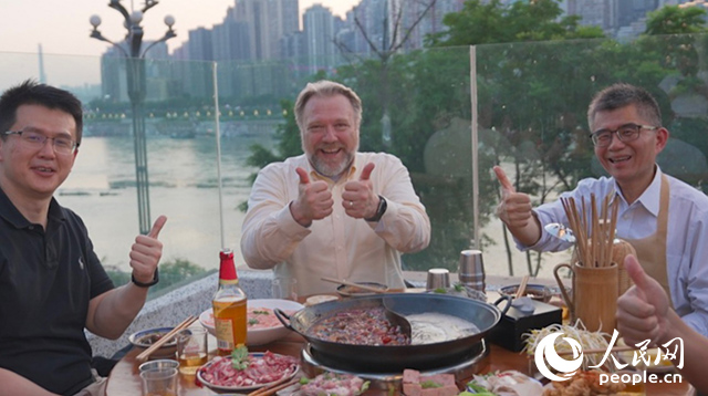 康寧顯示科技事業(yè)部全球拓建項(xiàng)目總監(jiān)軻寶華（中）和同事在重慶南濱路吃火鍋。人民網(wǎng)記者 蘇纓翔攝