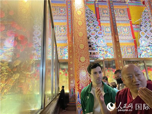 7月25日，省級(jí)非物質(zhì)文化遺產(chǎn)項(xiàng)目塔爾寺酥油花的代表性傳承人朋措堅(jiān)參（右）在塔爾寺酥油花館講解酥油花的制作過程。人民網(wǎng) 謝瑩攝