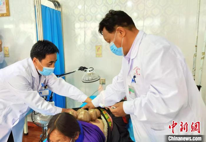 圖為看照加手把手帶徒弟加老(左一)進(jìn)行拔罐療法。　張婧 攝