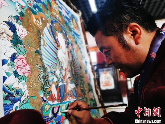 圖為久美尖措創(chuàng)作唐卡?！?zhí)砀?攝