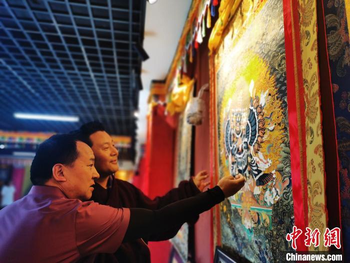 圖為久美尖措展示唐卡作品?！?zhí)砀?攝