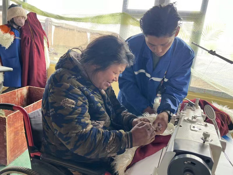 扎西奪爾登幫助殘疾員工裁剪。阿壩州文明辦供圖