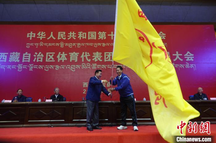 西藏自治區(qū)副主席甲熱·洛桑丹增授代表團團旗，西藏自治區(qū)體育局局長尼瑪次仁接旗。　冉文娟 攝