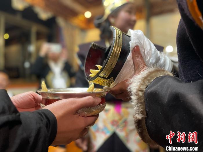 圖為主人在碗中斟滿青稞酒?！∪轿木?攝