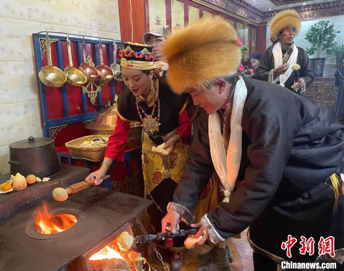 圖為人們在火上烤節(jié)日美食“結達”?！∪轿木?攝