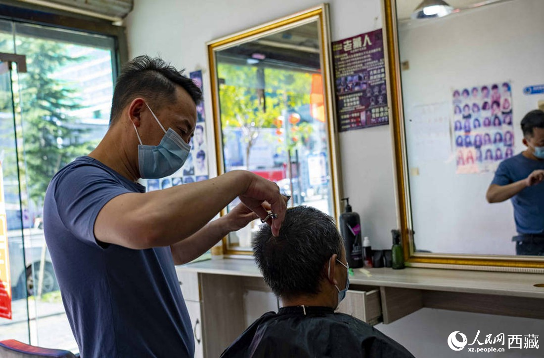 理發(fā)店老板為顧客理發(fā)。次仁羅布 攝