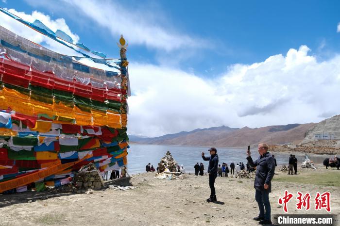 進(jìn)藏參訪嘉賓在羊湖畔拍攝經(jīng)幡?！〗w波 攝