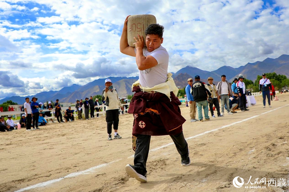 來自拉薩市當(dāng)雄縣的牧民選手將一塊150斤重的石頭扛在肩上飛奔。