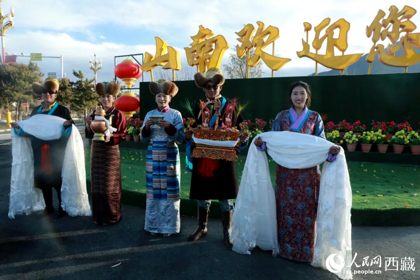 扎西曲登社區(qū)的居民在“山南歡迎您”標(biāo)志前，手持潔白哈達(dá)和切瑪，列隊(duì)迎接來自區(qū)內(nèi)外的游客，用最隆重的禮儀開啟一場(chǎng)沉浸式藏歷新年民俗體驗(yàn)之旅。人民網(wǎng)記者 吳雨仁攝