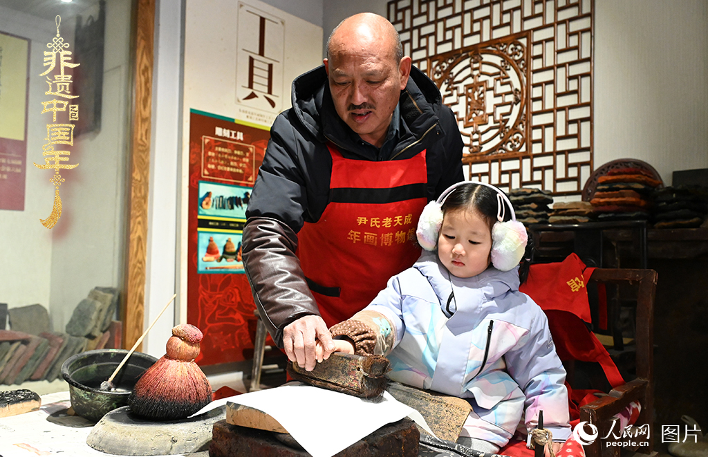 2025年1月27日，河南開封朱仙鎮(zhèn)木版年畫藝人尹國法指導(dǎo)小朋友研習(xí)年畫印制技藝。朱仙鎮(zhèn)木版年畫源自漢唐壁畫藝術(shù)，是中國木版年畫的鼻祖。2006年5月20日，朱仙鎮(zhèn)木版年畫經(jīng)國務(wù)院批準(zhǔn)列入第一批國家級(jí)非物質(zhì)文化遺產(chǎn)名錄。人民網(wǎng)記者 王玉興攝