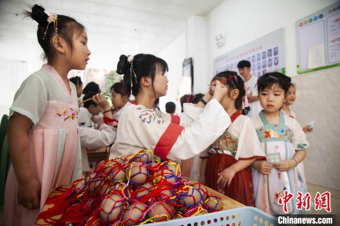 圖為幼兒園的老師們穿上漢服為小朋友們戴上彩蛋，寓意著幸福安康?！《^生 攝